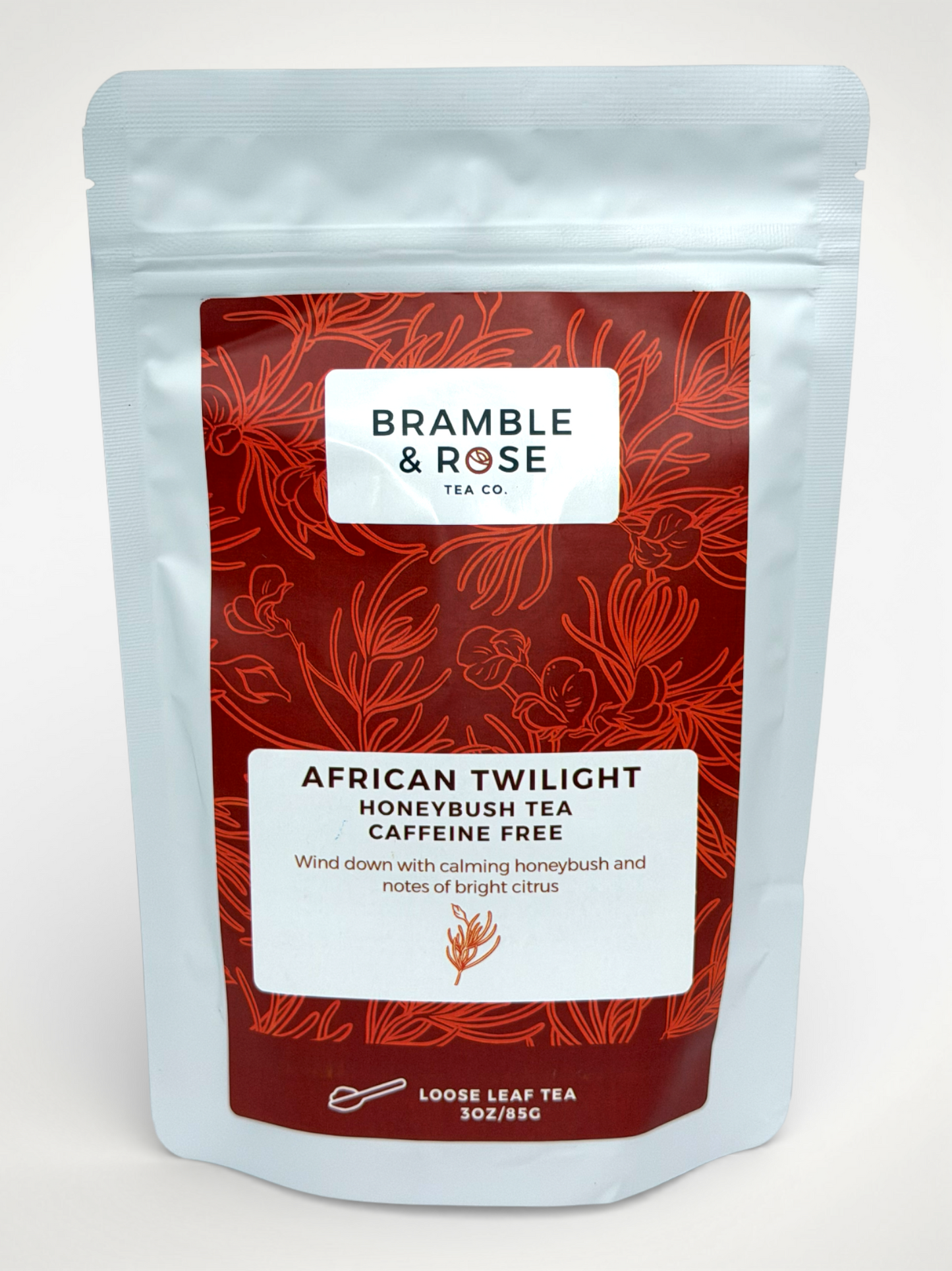 White pouch of Bramble & Rose African Twilight Honeybush Tea, with a red design featuring plant illustrations, a white rectangle with product description, and the "Bramble & Rose" logo.