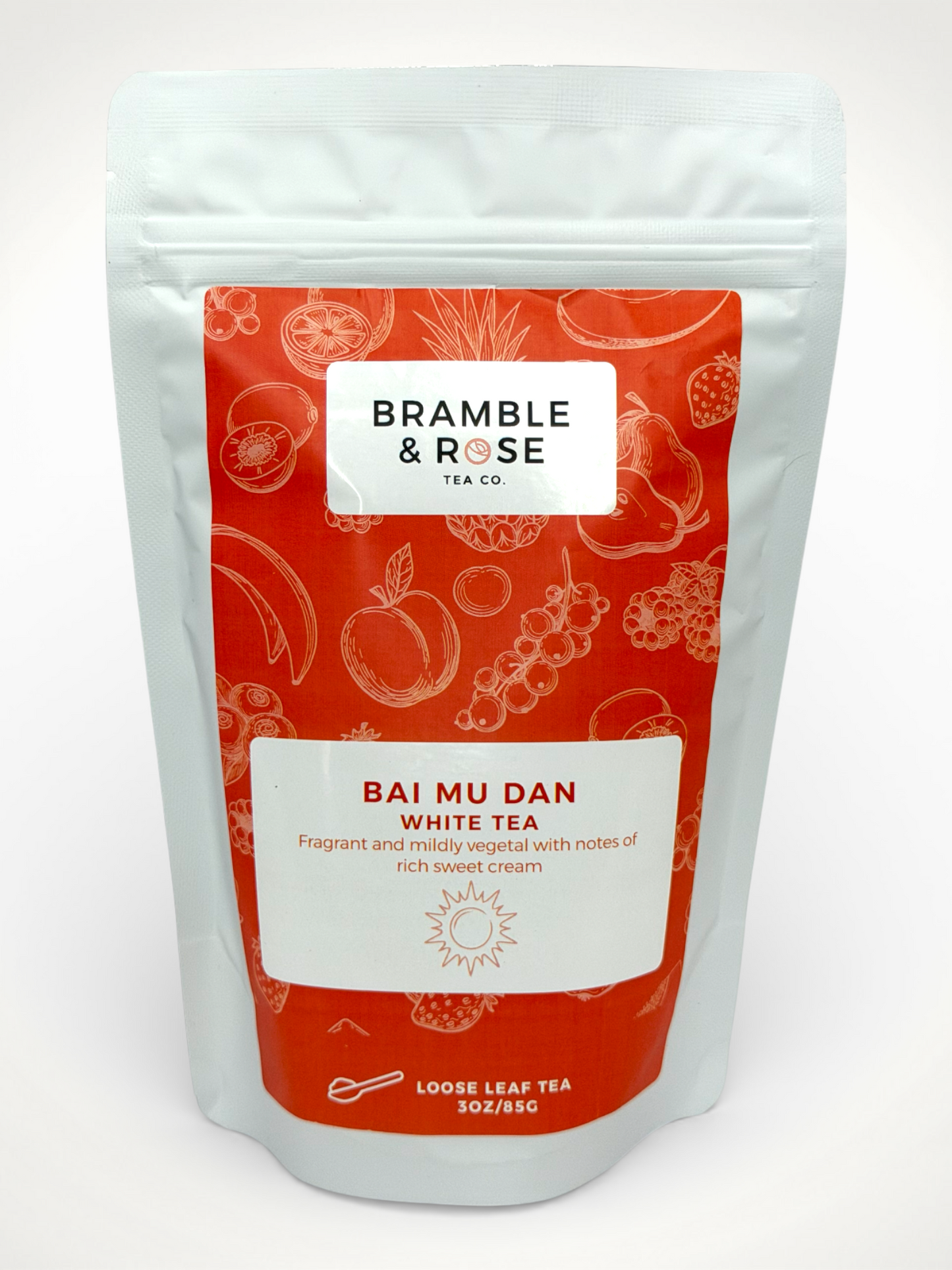 White pouch of Bramble & Rose Bai Mu Dan White Tea, with a coral design featuring fruit illustrations, a white rectangle with product description, and the "Bramble & Rose" logo.