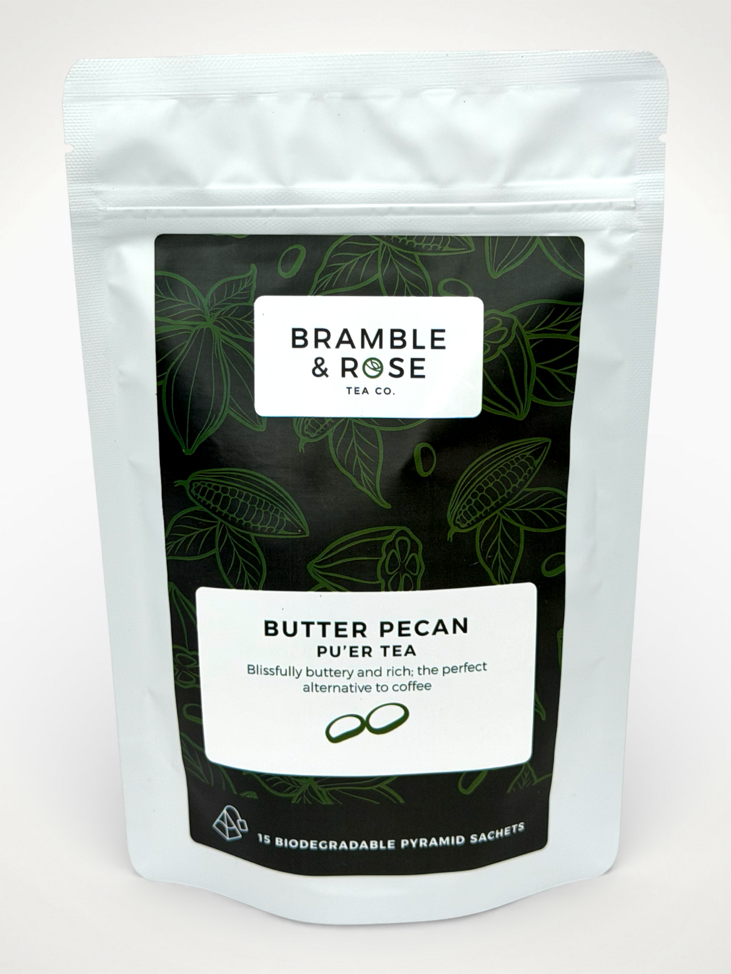 White pouch of Bramble & Rose Butter Pecan Pu'er Tea, with a dark green label design featuring tea leaf and cacao pod illustrations, a white rectangle with product description, and the "Bramble & Rose" logo.