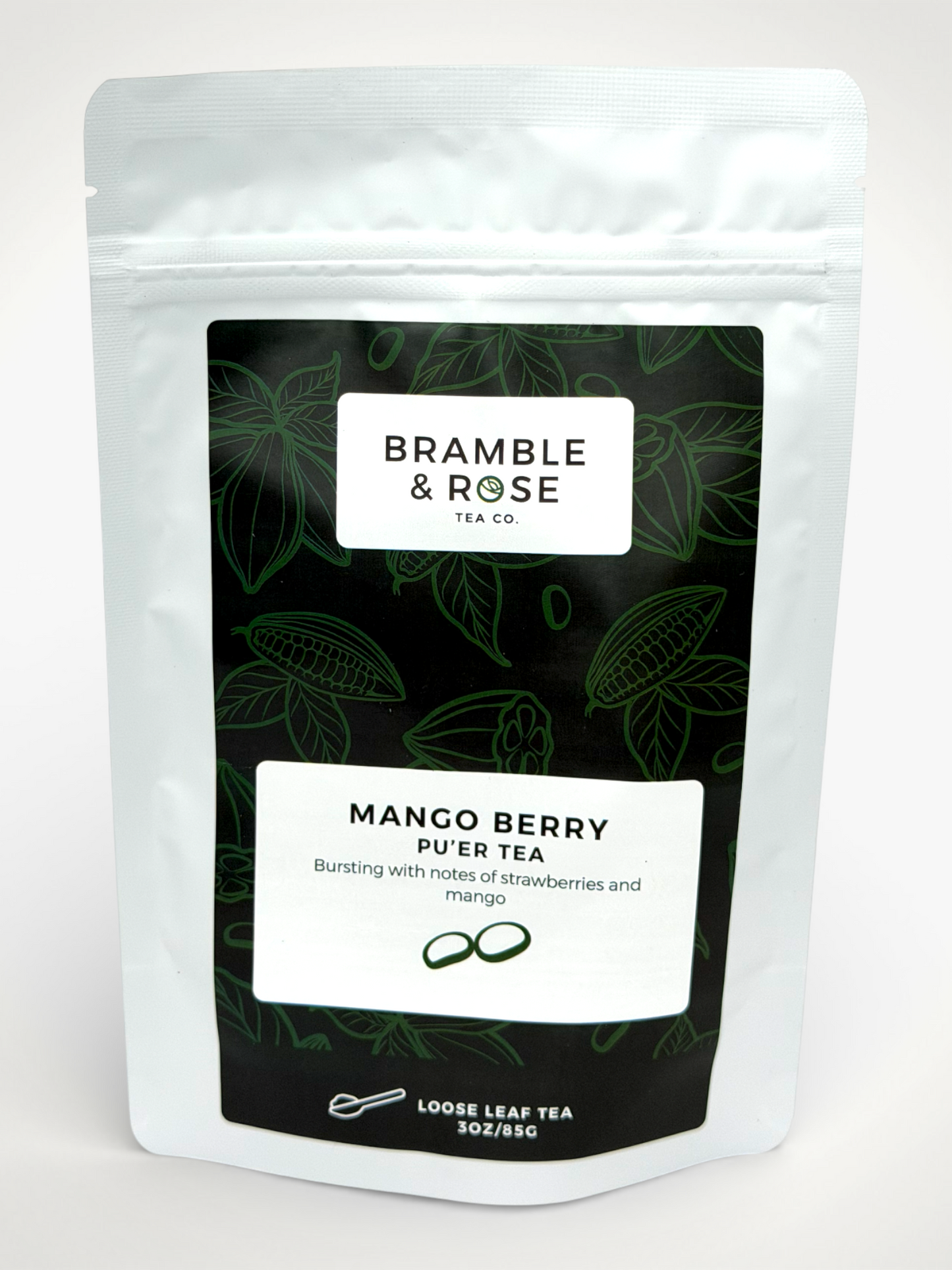 White pouch of Bramble & Rose Mango Berry Pu'Er Tea featuring a dark green background with tea leaf illustrations, a white rectangle with product description, and the "Bramble & Rose" logo.