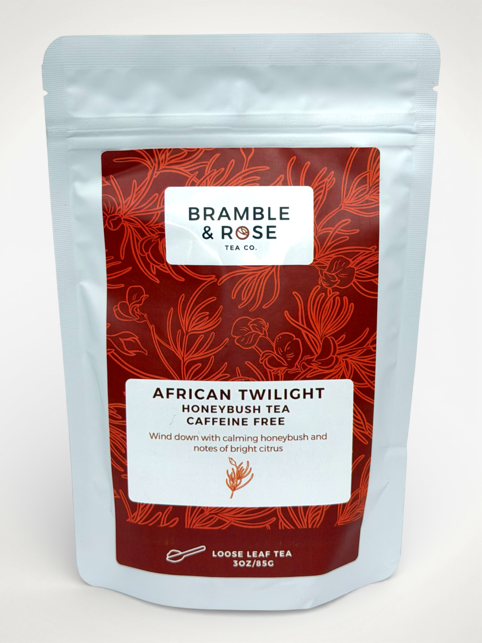White pouch of Bramble & Rose African Twilight Honeybush Tea, with a red design featuring plant illustrations, a white rectangle with product description, and the "Bramble & Rose" logo.
