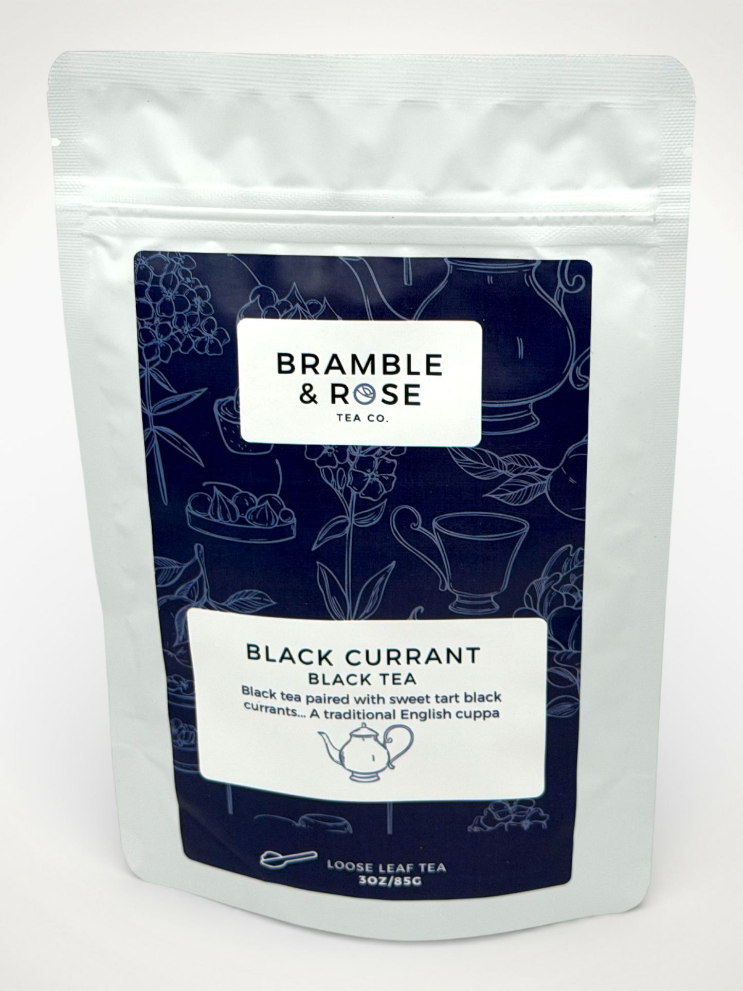 White pouch of Bramble & Rose Black Currant Black Tea, with a dark blue label featuring tea themed illustrations, a white rectangle with product description, and the "Bramble & Rose" logo.