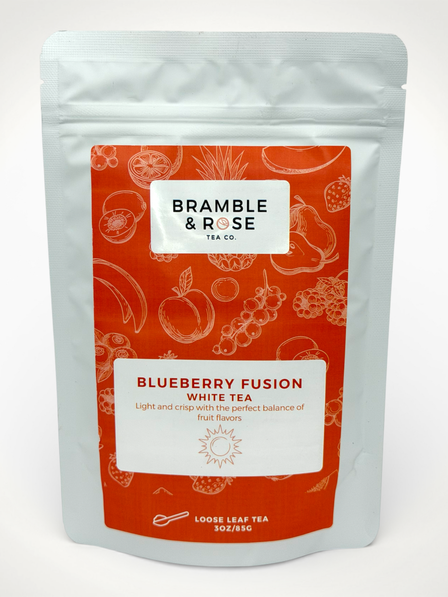 White pouch of Bramble & Rose Blueberry Fusion White Tea, with a coral label featuring fruit illustrations, a white rectangle with product description, and the "Bramble & Rose" logo.