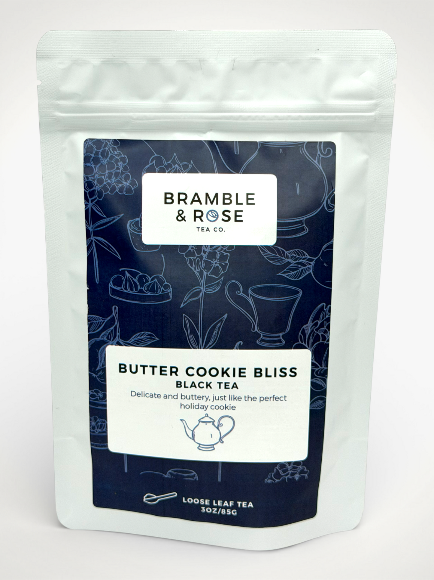 White pouch of Bramble & Rose Butter Cookie Bliss Black Tea, with a Dark Blue design featuring tea themed illustrations, a white rectangle with product description, and the "Bramble & Rose" logo.