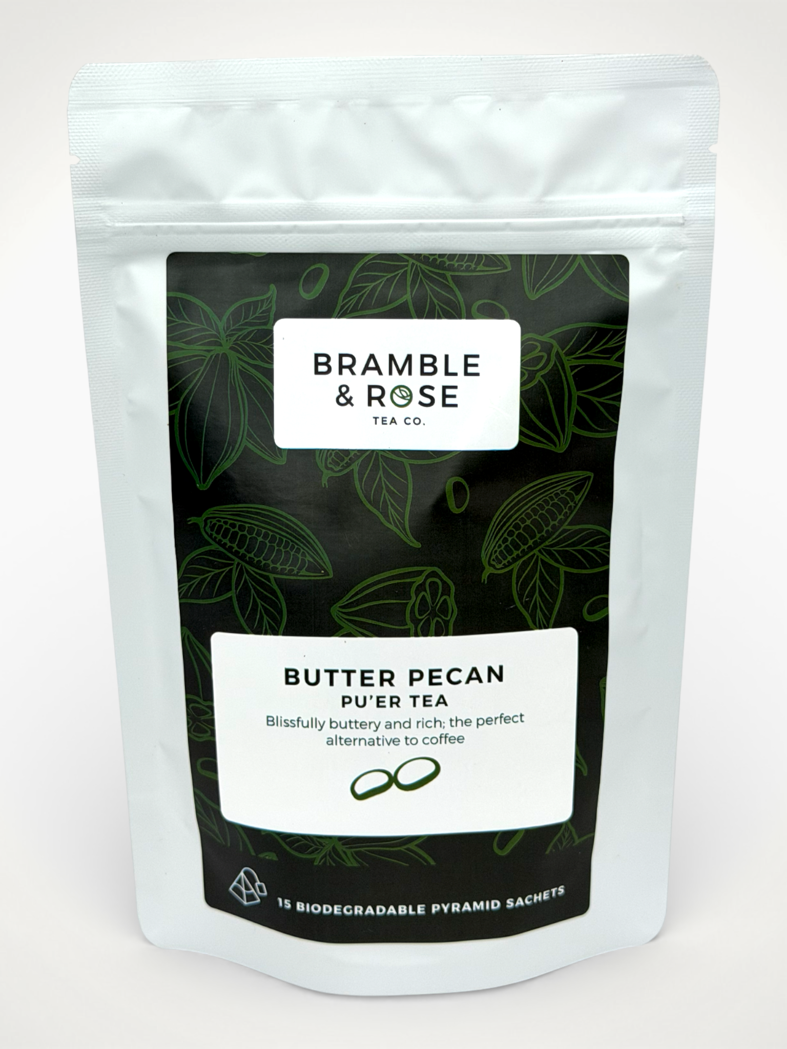White pouch of Bramble & Rose Butter Pecan Pu'er Tea, with a dark green label design featuring tea leaf and cacao pod illustrations, a white rectangle with product description, and the "Bramble & Rose" logo.