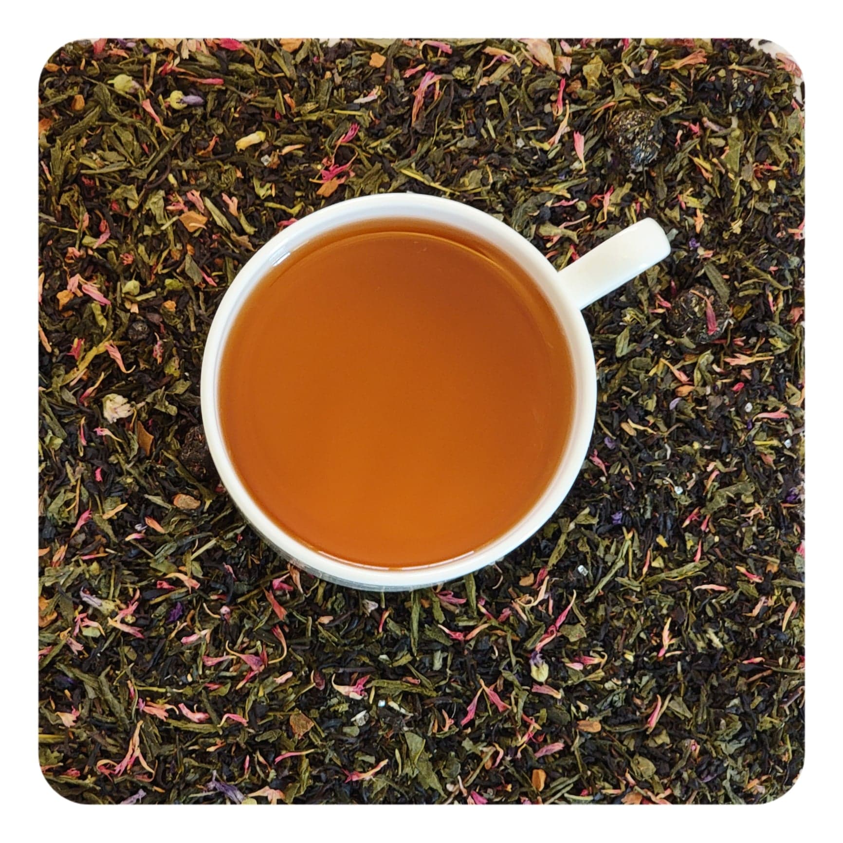 An overhead image of dried Bramble & Rose Tea Co. Blueberry Buckle Green tea loose leaf tea including dried green and black tea leaves, blueberries, and red flower petals . There is a white teacup in the center with a gold/orange liquid of steeped Blueberry Buckle green tea