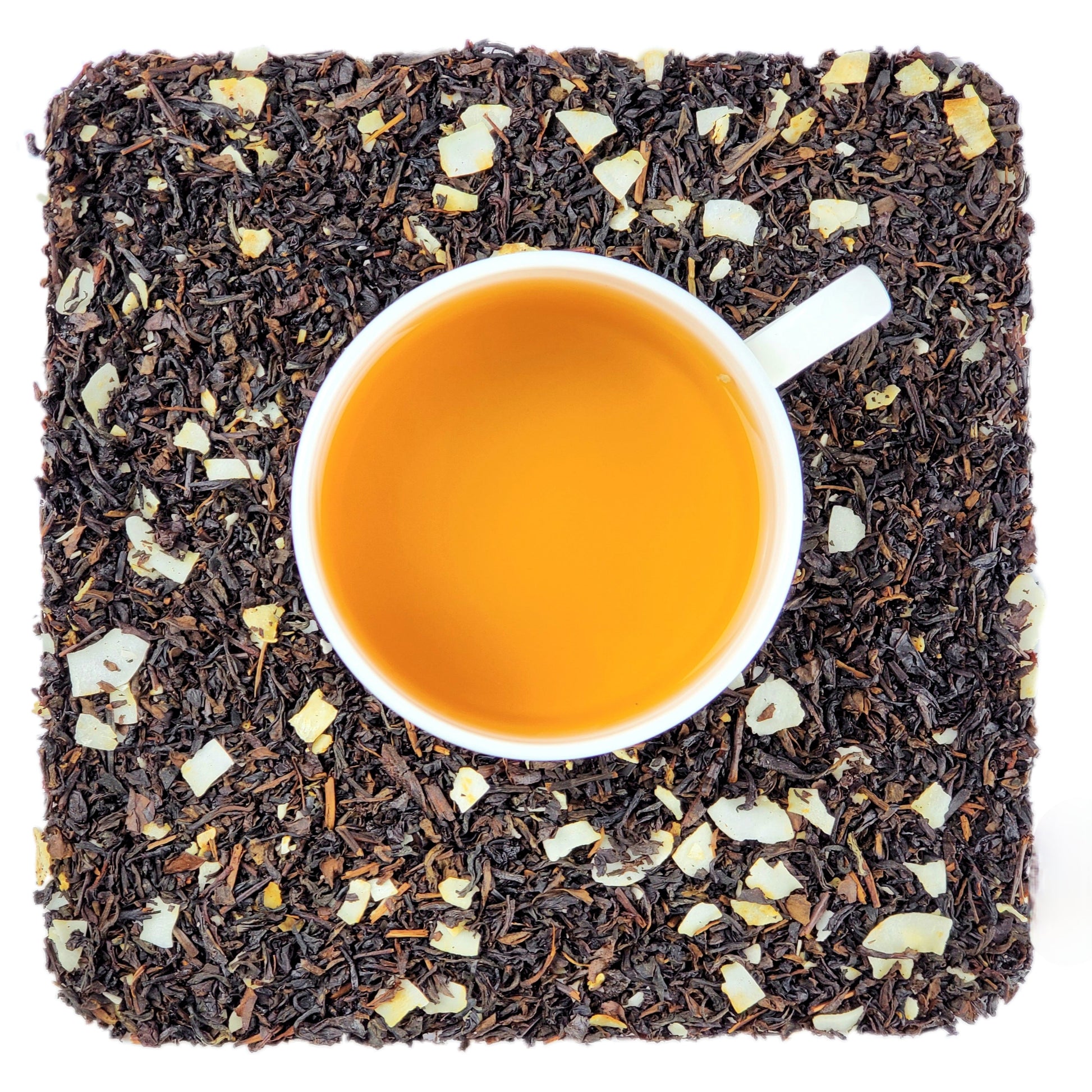 A cup of brewed tea on a bed of shaved coconut and dried oolong tea leaves.