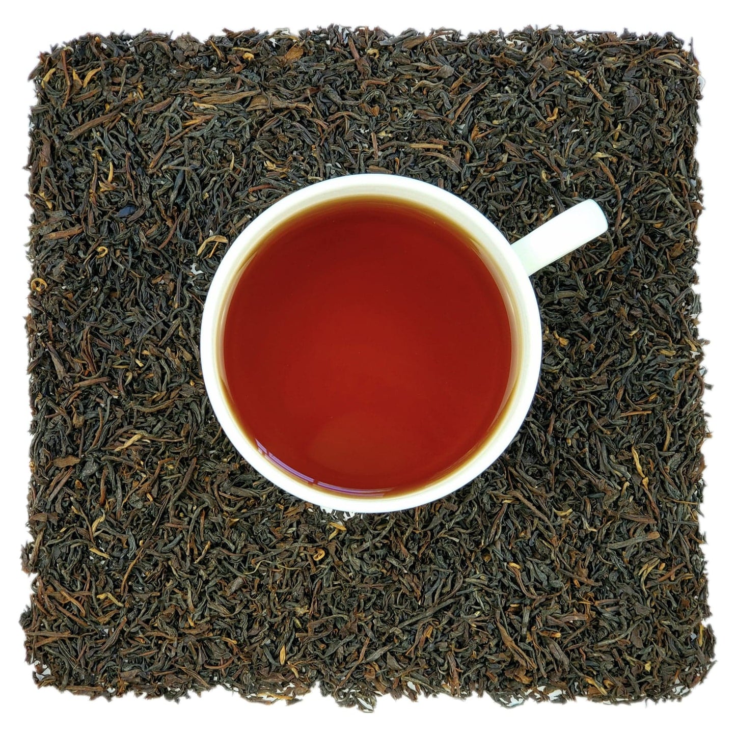 A cup of brewed black tea placed in the center with loose black tea leaves spread around it.