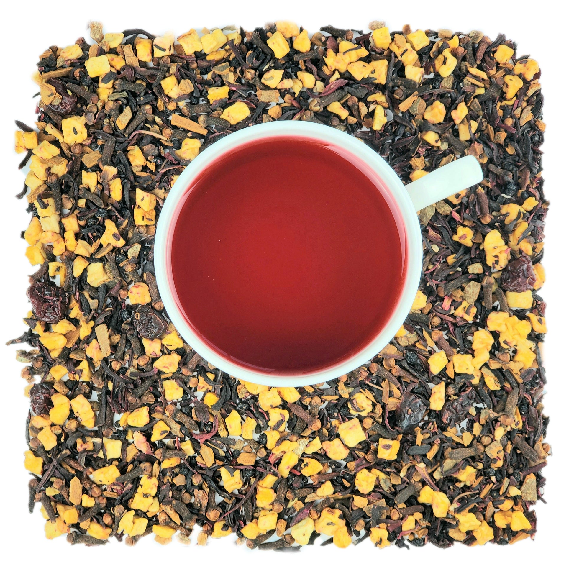 A cup of brewed tea surrounded by dried hibiscus, cranberries, cloves, cinnamon, and apple pieces on a white background.