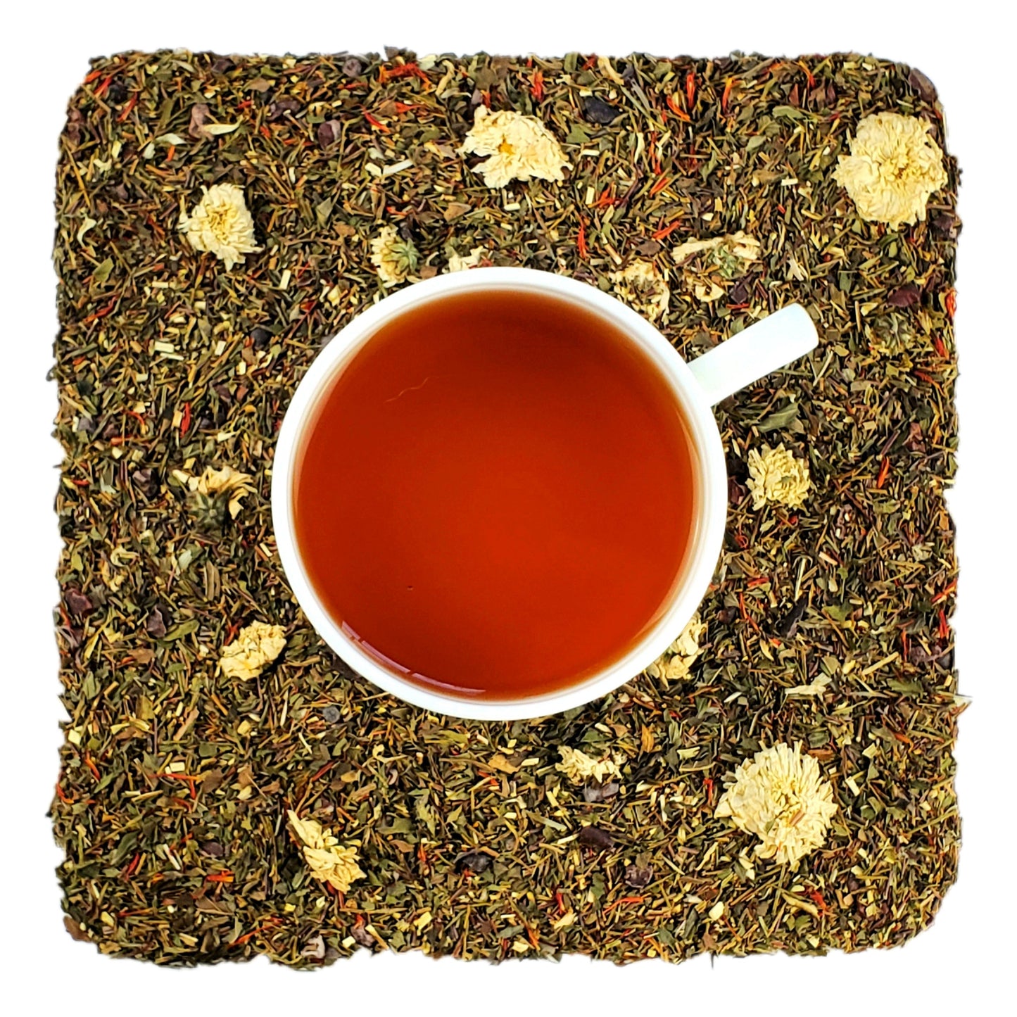 A cup of peppermint mocha tea with dried green rooibos leaves, flowers and pieces of cacao around it, indicating the ingredients of the tea blend.
