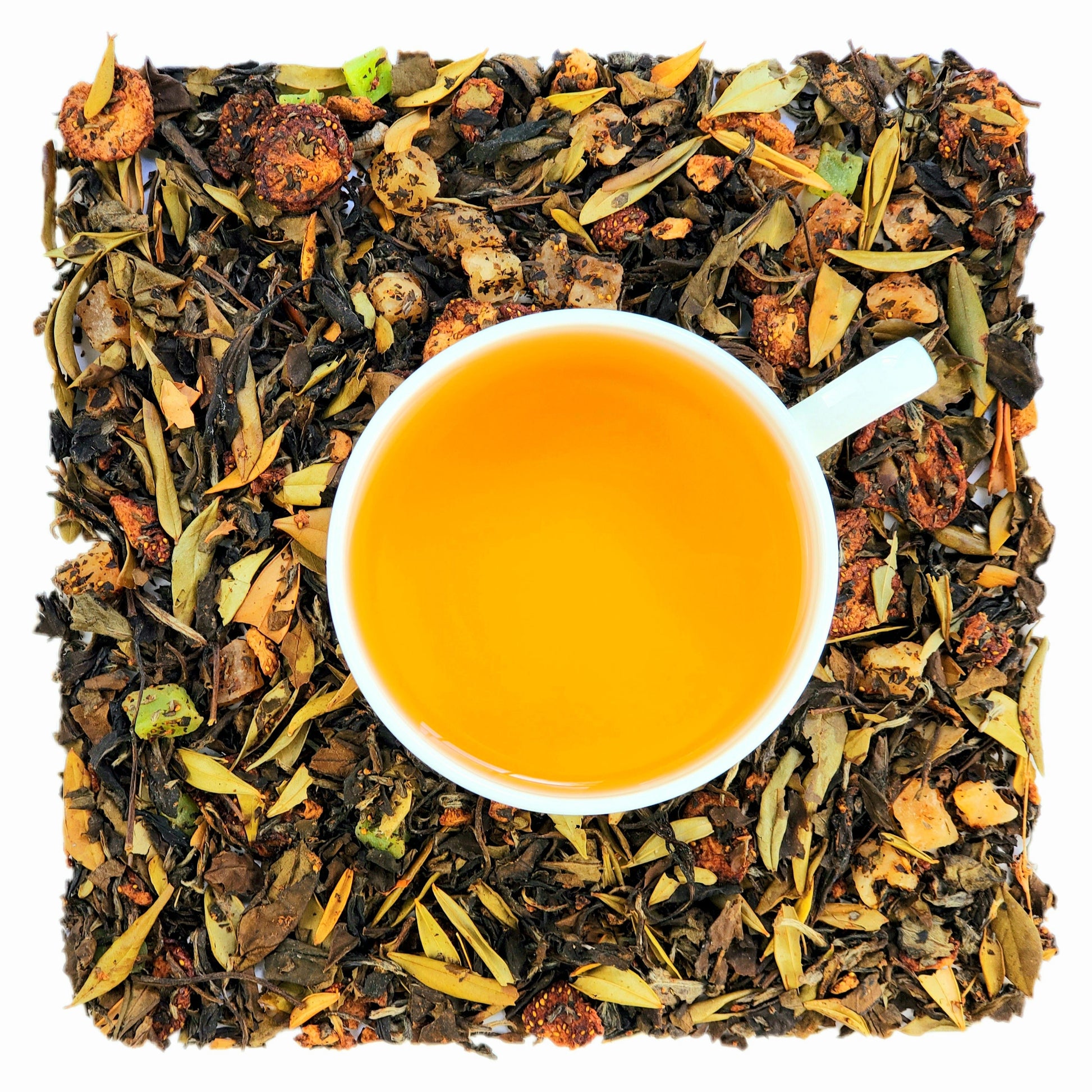 A cup of strawberry kiwi quencher brewed tea on a bed of loose white tea leaves with dried pieces of strawberry, pineapple, and kiwi. 